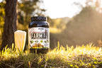 Axe & Sledge Farm Fed vassleproteinisolat i burk med svart lock, utomhus på gräs