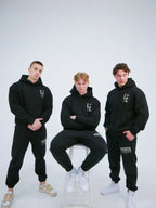 Svart hoodie med L:C-tryck, visad på tre modeller i helfigur