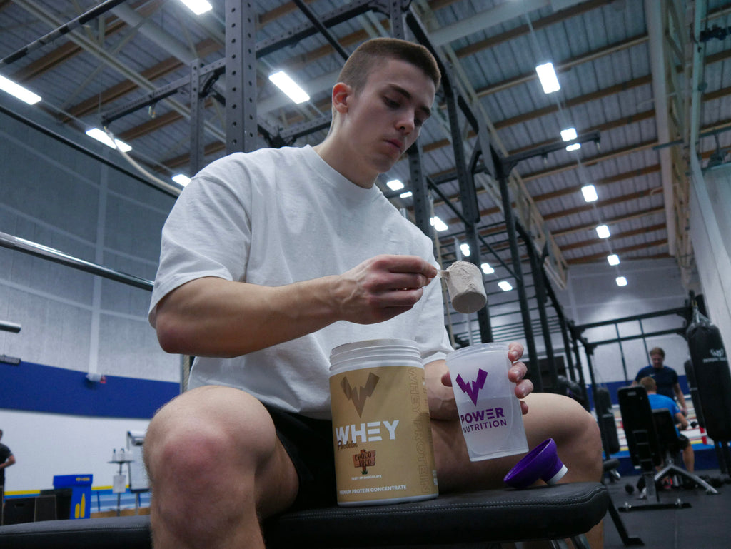 Kille på gymmet håller i en burk POWER WHEY