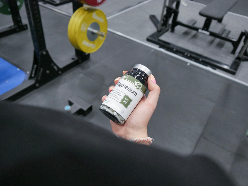 Tjej Håller i Elexir Pharma Magnesium på gymmet