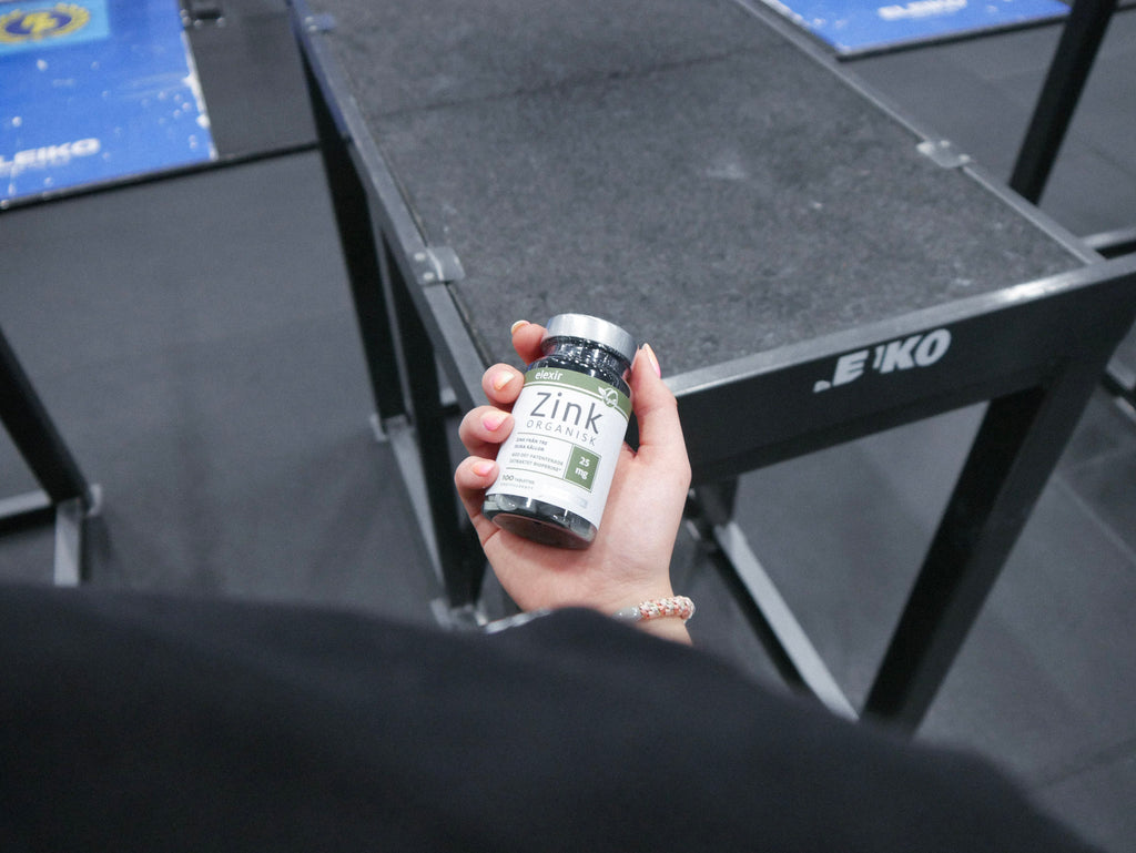 Tjej håller i Elexir Pharma Organisk Zink på gymmet